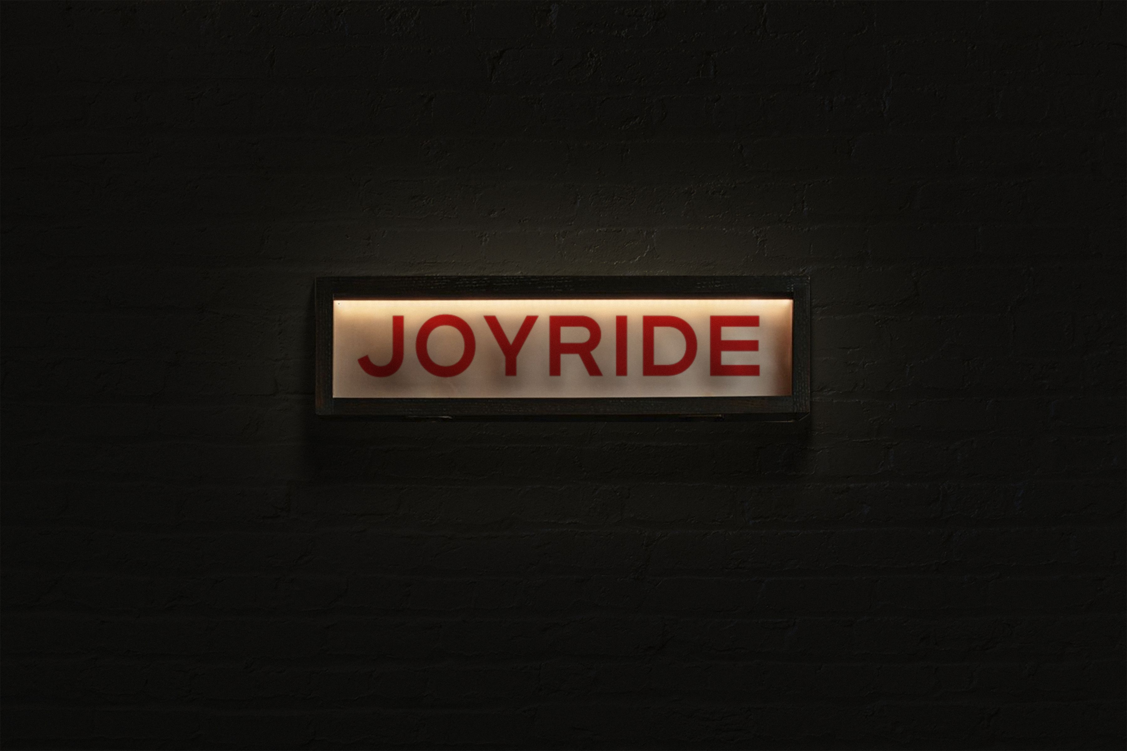 A light up box hanging on a wall that reads "Joyride"
