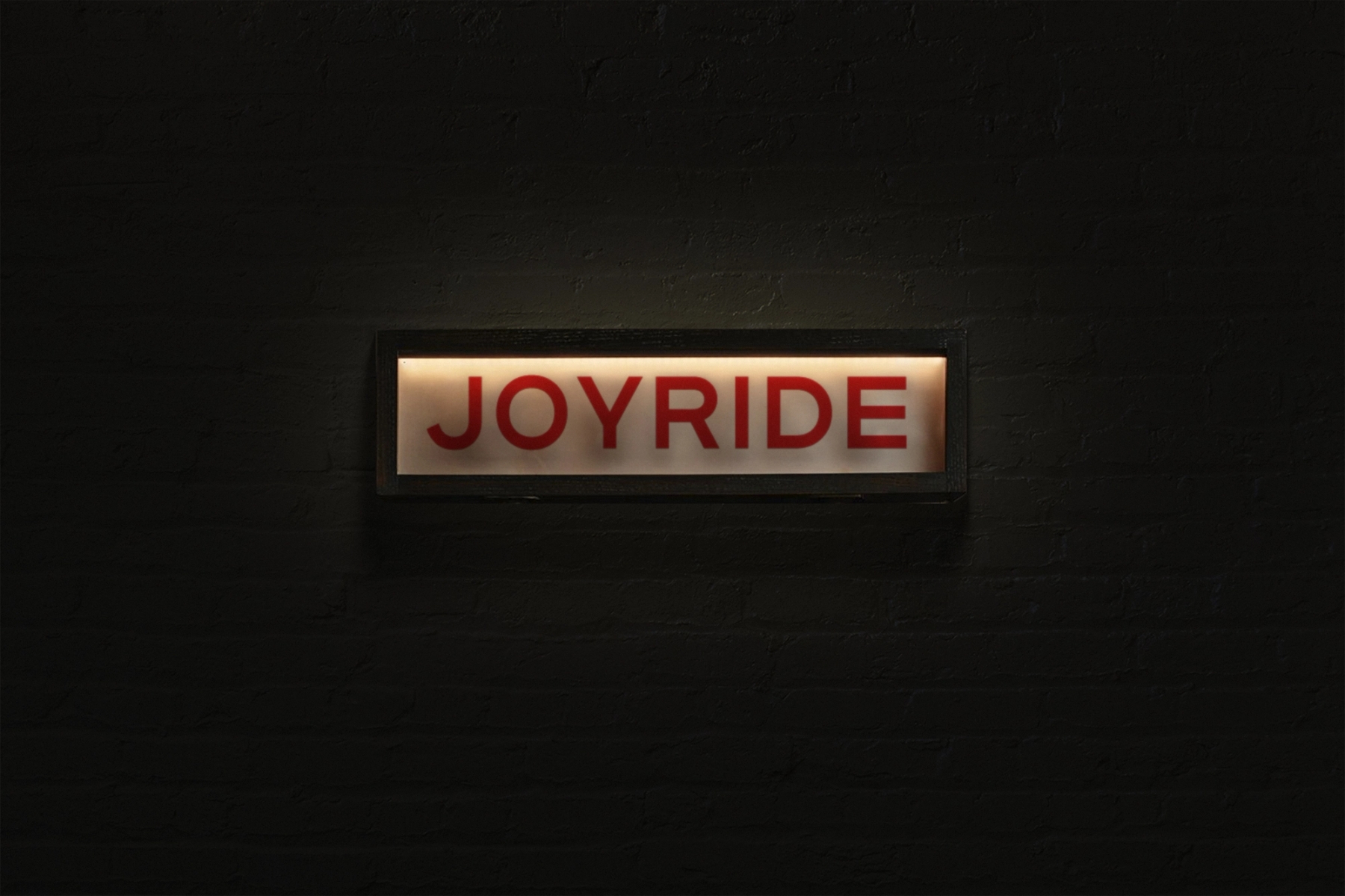 A light up box hanging on a wall that reads "Joyride"