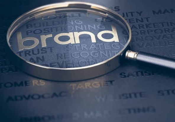 Magnifying glass examining the word "brand" surrounded by positioning, strategy, and recognition keywords