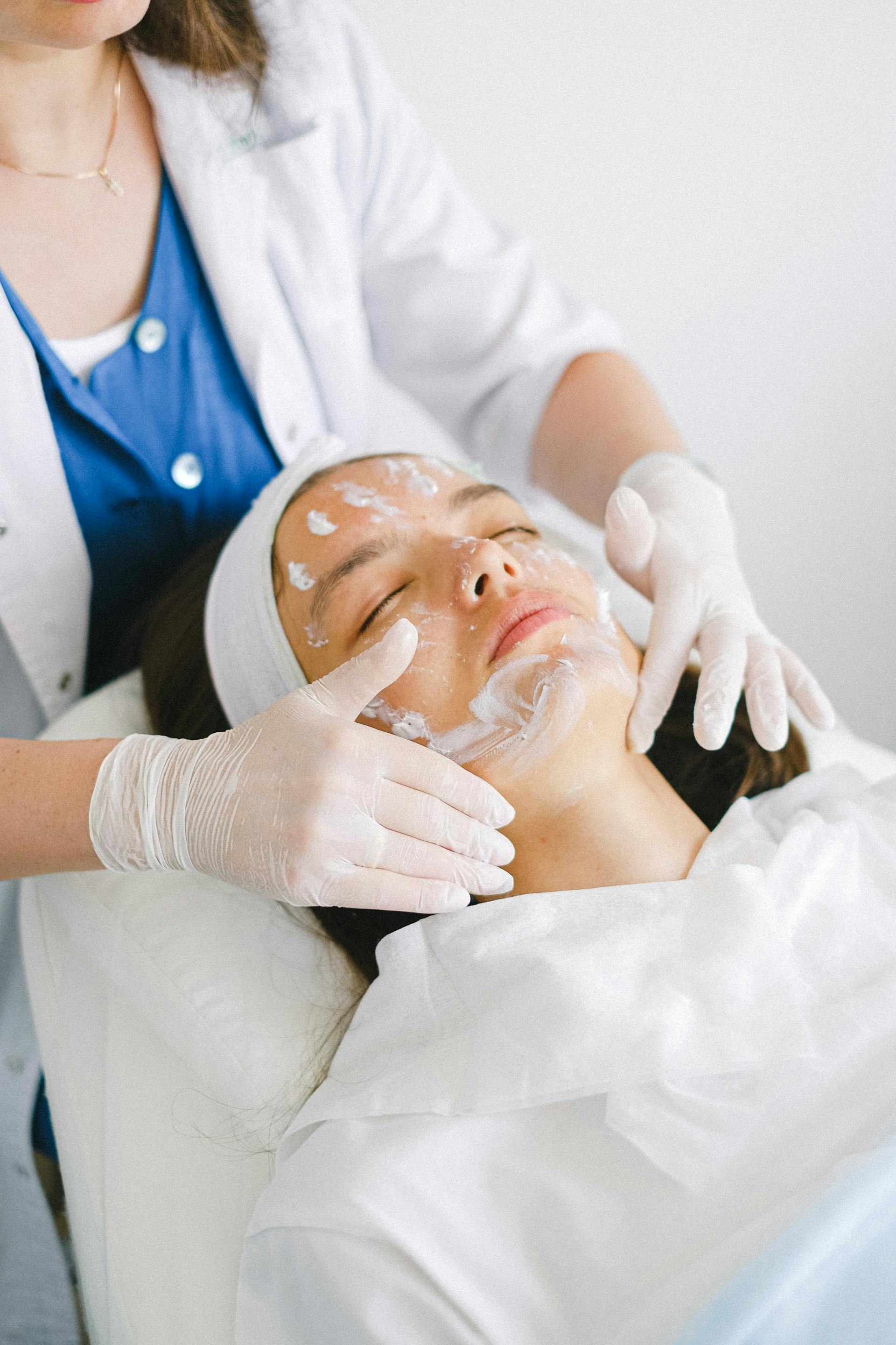 Cosmetologist applying facial mask treatment in spa salon