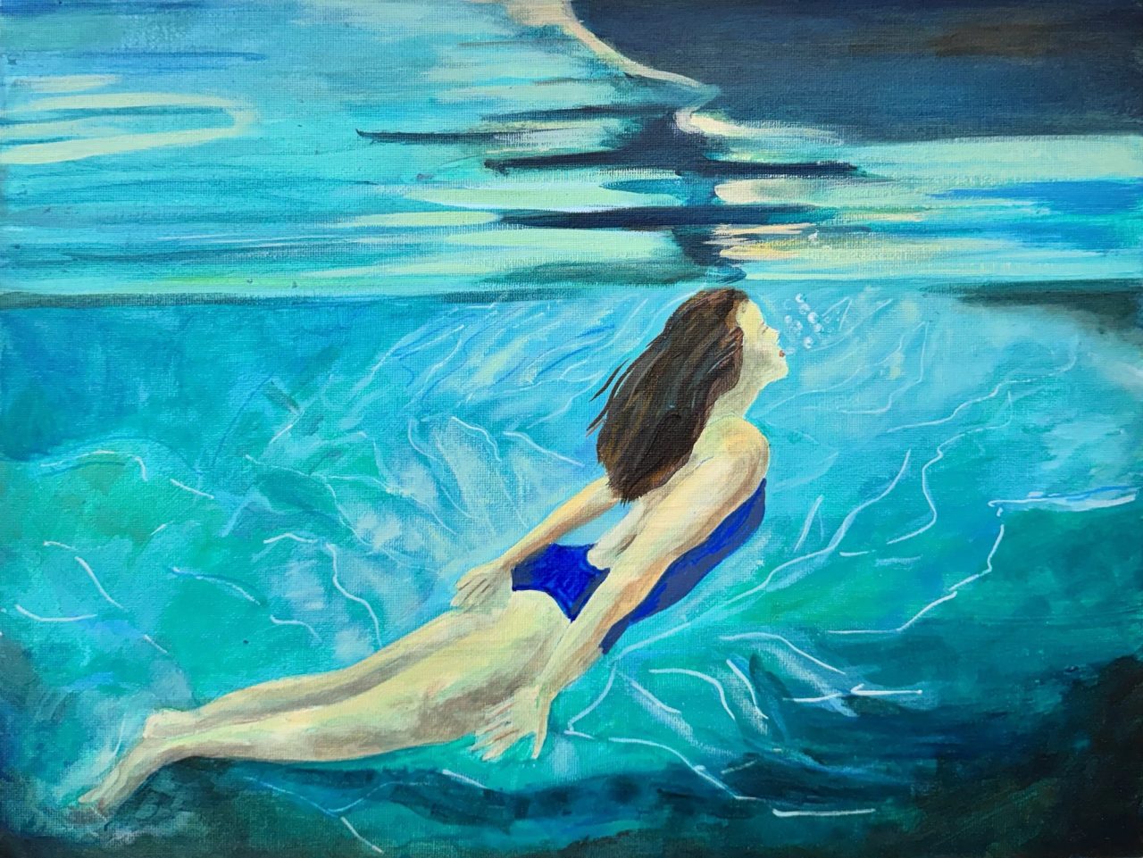 A woman swimming underwater in a blue swimsuit, light rippling on the surface above