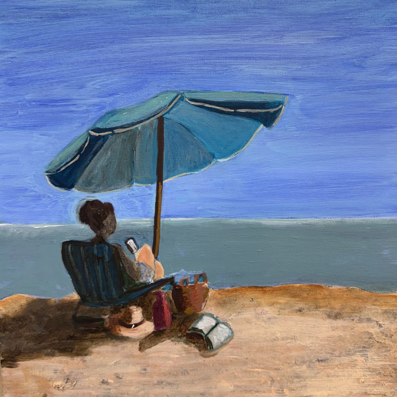 A woman reading in a beach chair under a blue umbrella at the edge of the sea