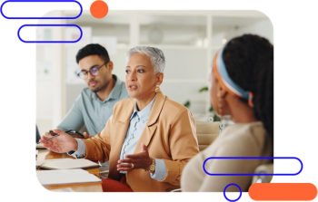 Person sat at a desk with two other people talking