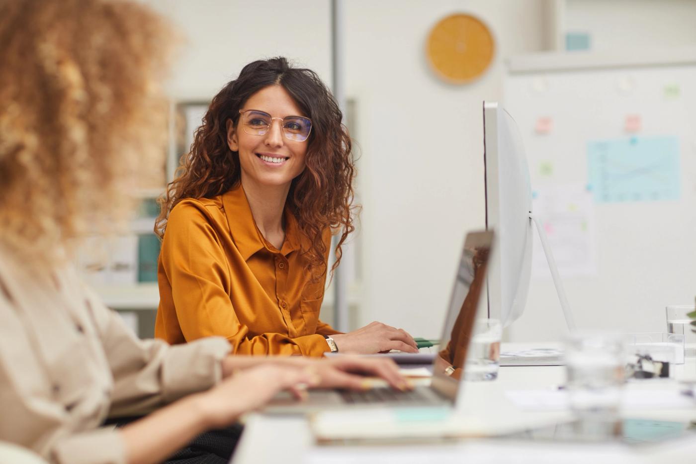 Eine Person, die lächelnd an einem Computer arbeitet