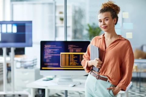 Person stood next to a computer desk holding a tablet device
