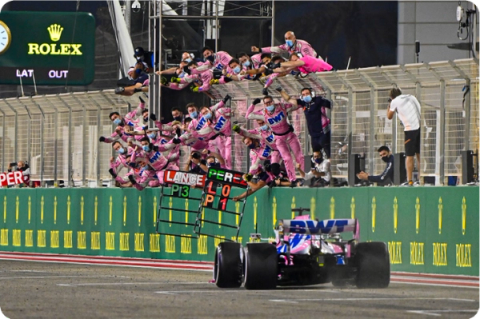 winning race car approaches teammates waiting at barriers to congratulate them