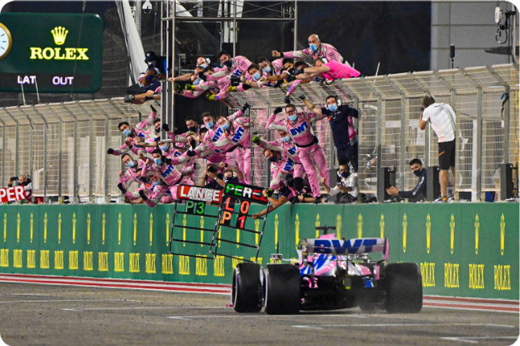 winning race car approaches teammates waiting at barriers to congratulate them