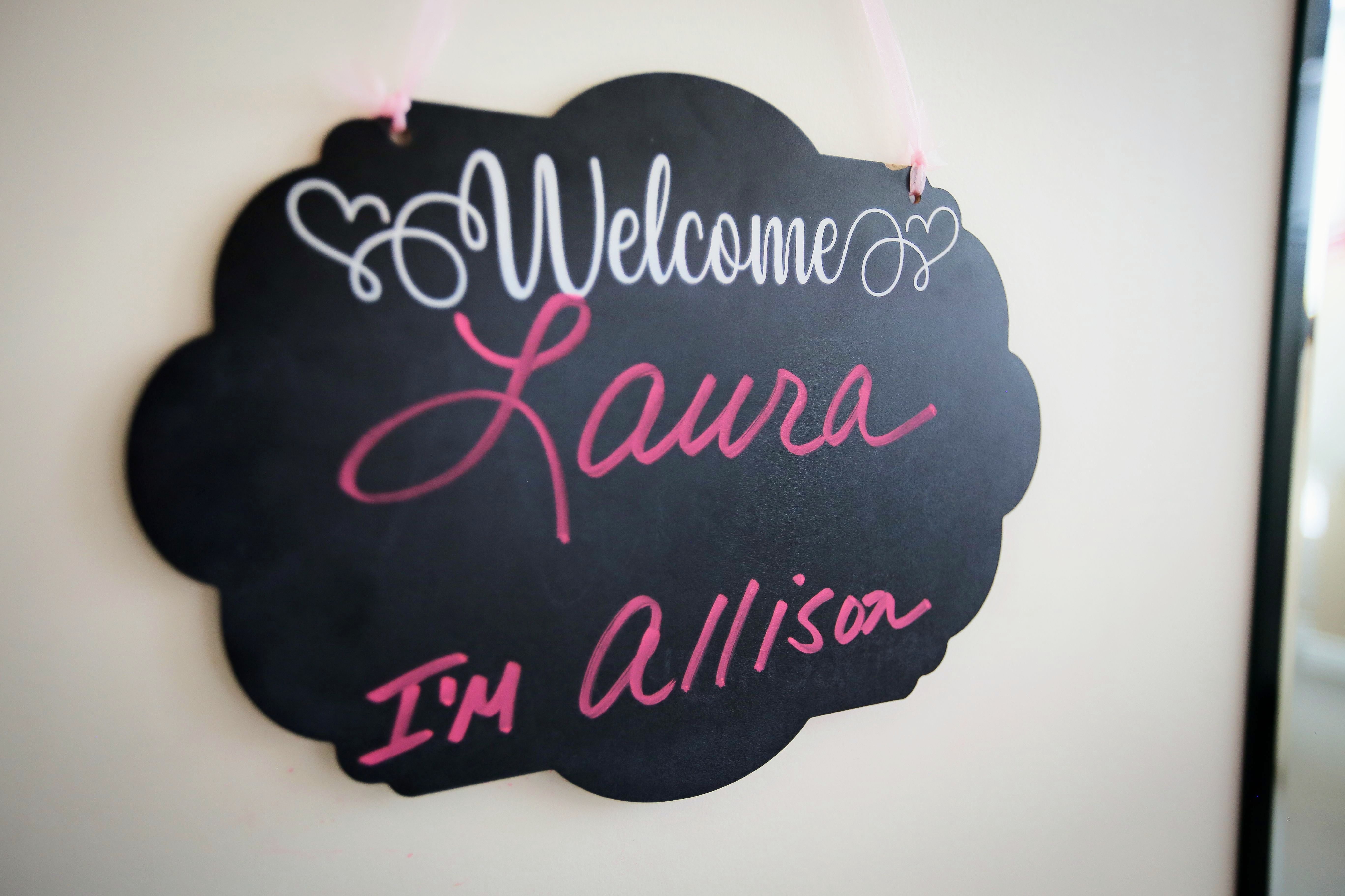 A chalkboard welcome sign greeting a bride by name at Aleana's Bridal