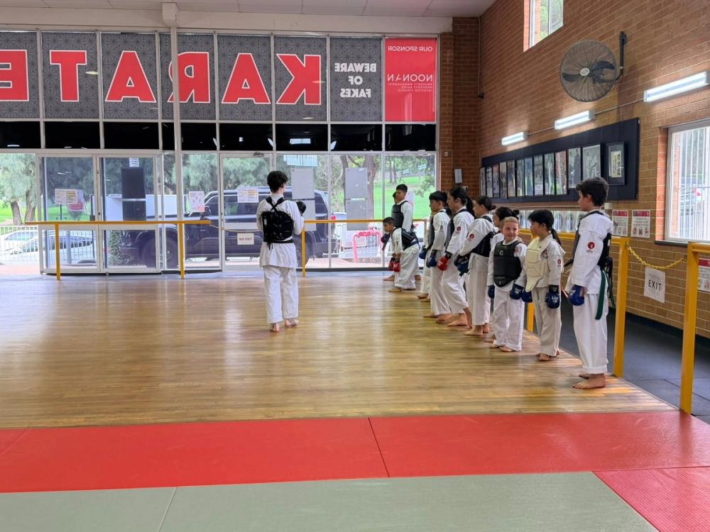 Kids in karate uniforms wearing protective gear lined up for sparring practice in a dojo