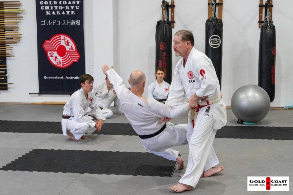 Chito-Ryu karate instructor demonstrating a throwing technique to students in a dojo