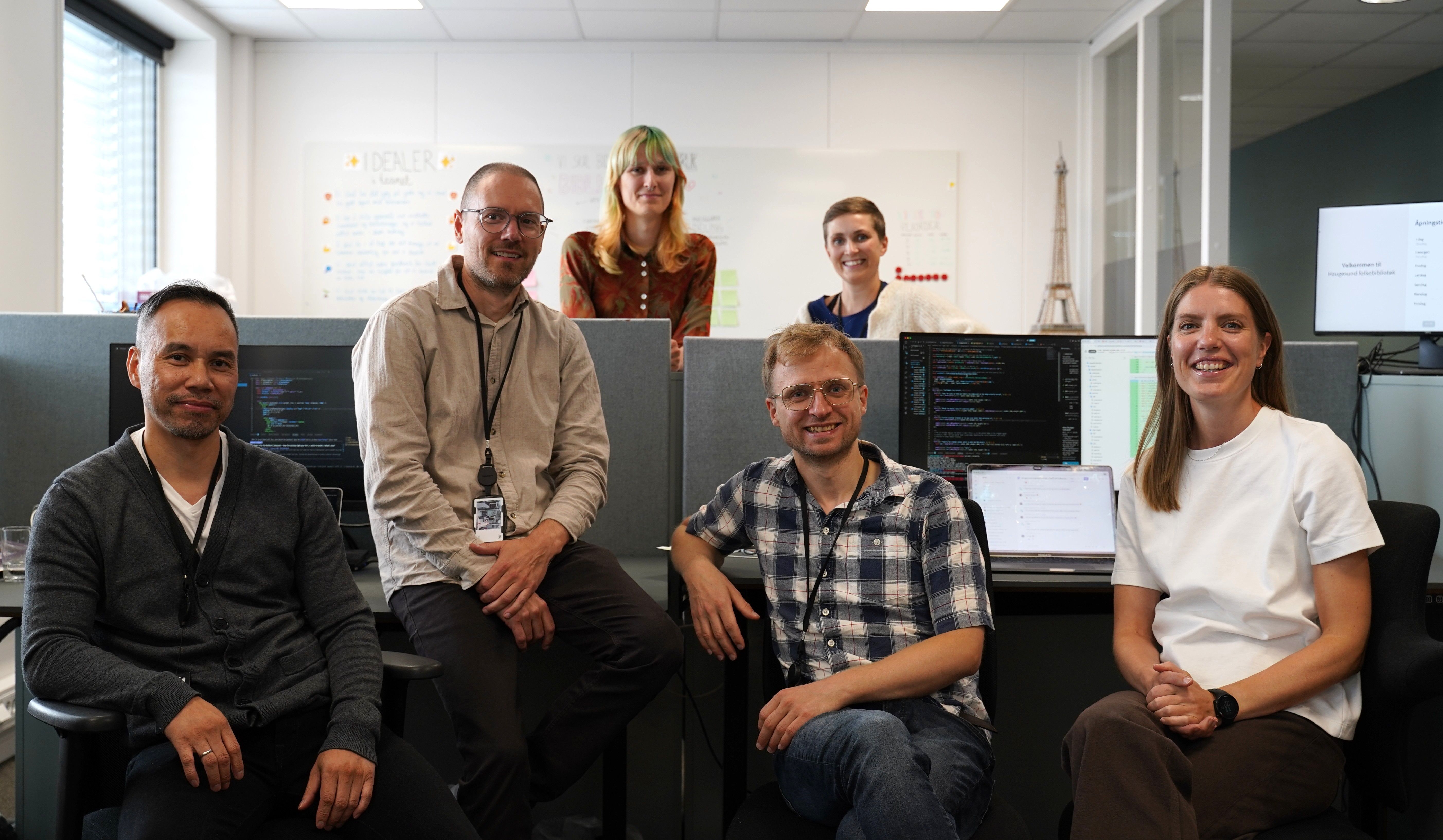 Six smiling people in an office.