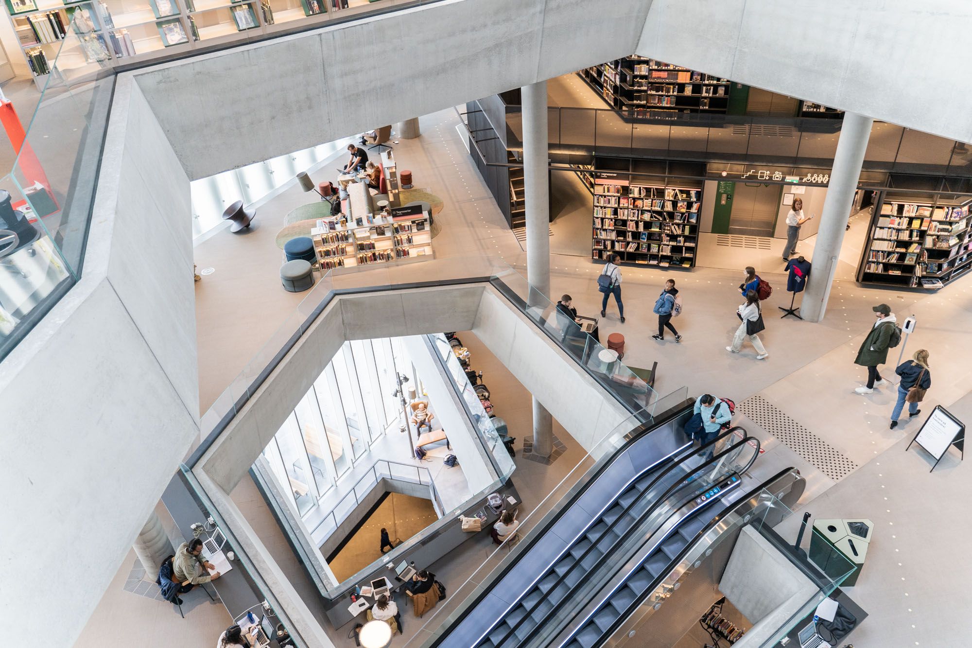 a group of people are walking down an escalator in a library .