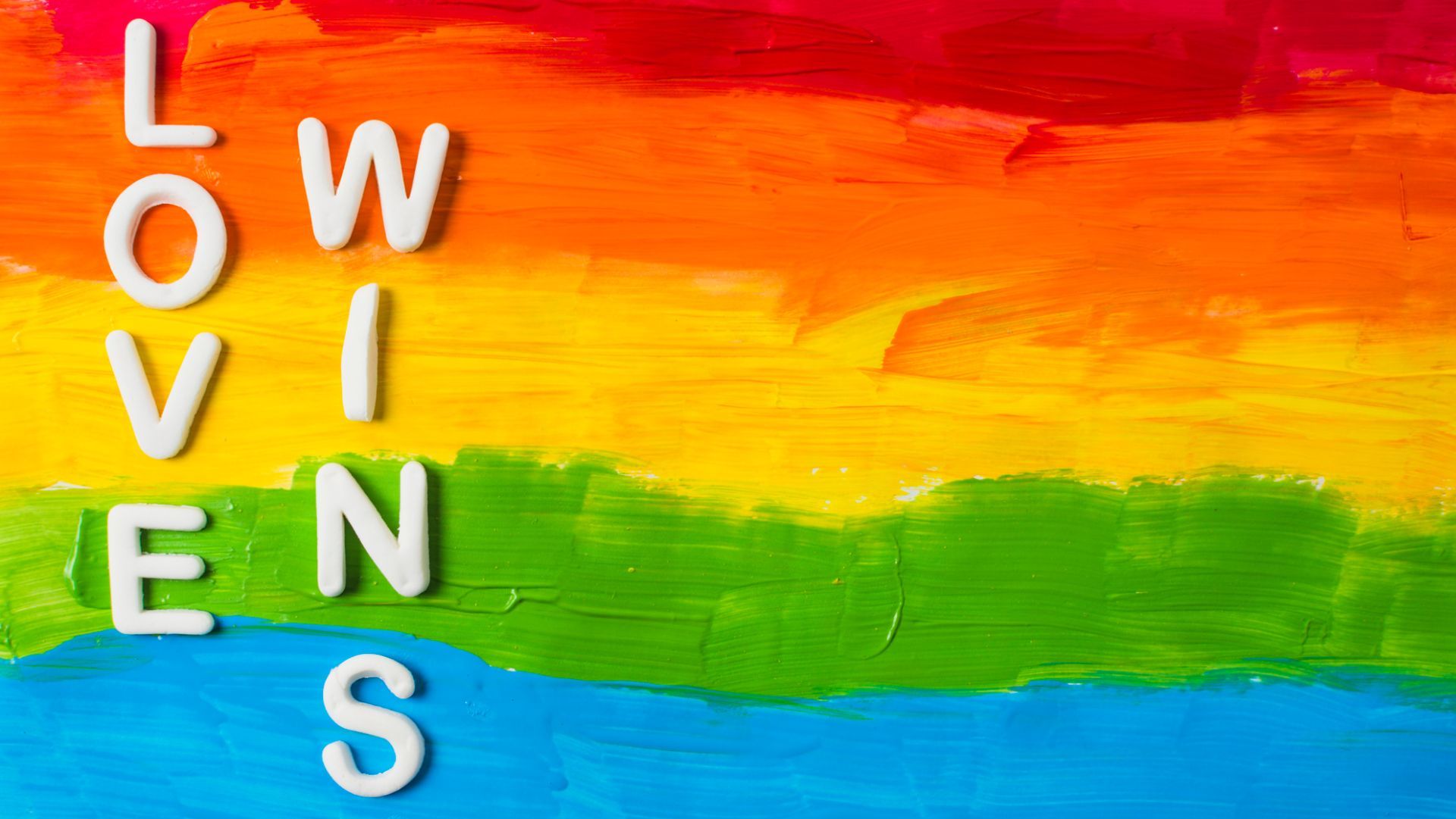 the word love is written in white letters on a colorful rainbow background .