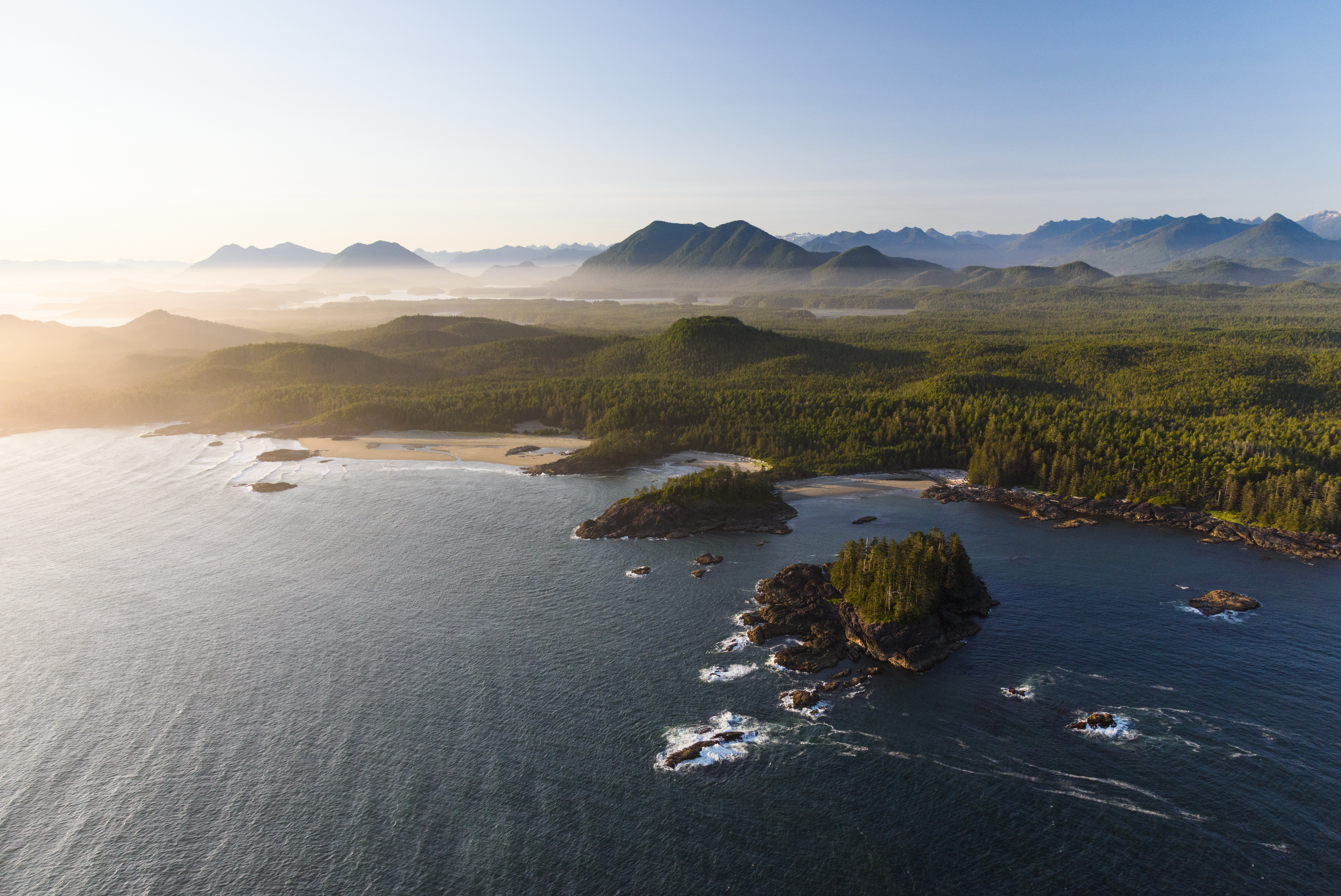 An overview of a mountainous setting, trees and open water