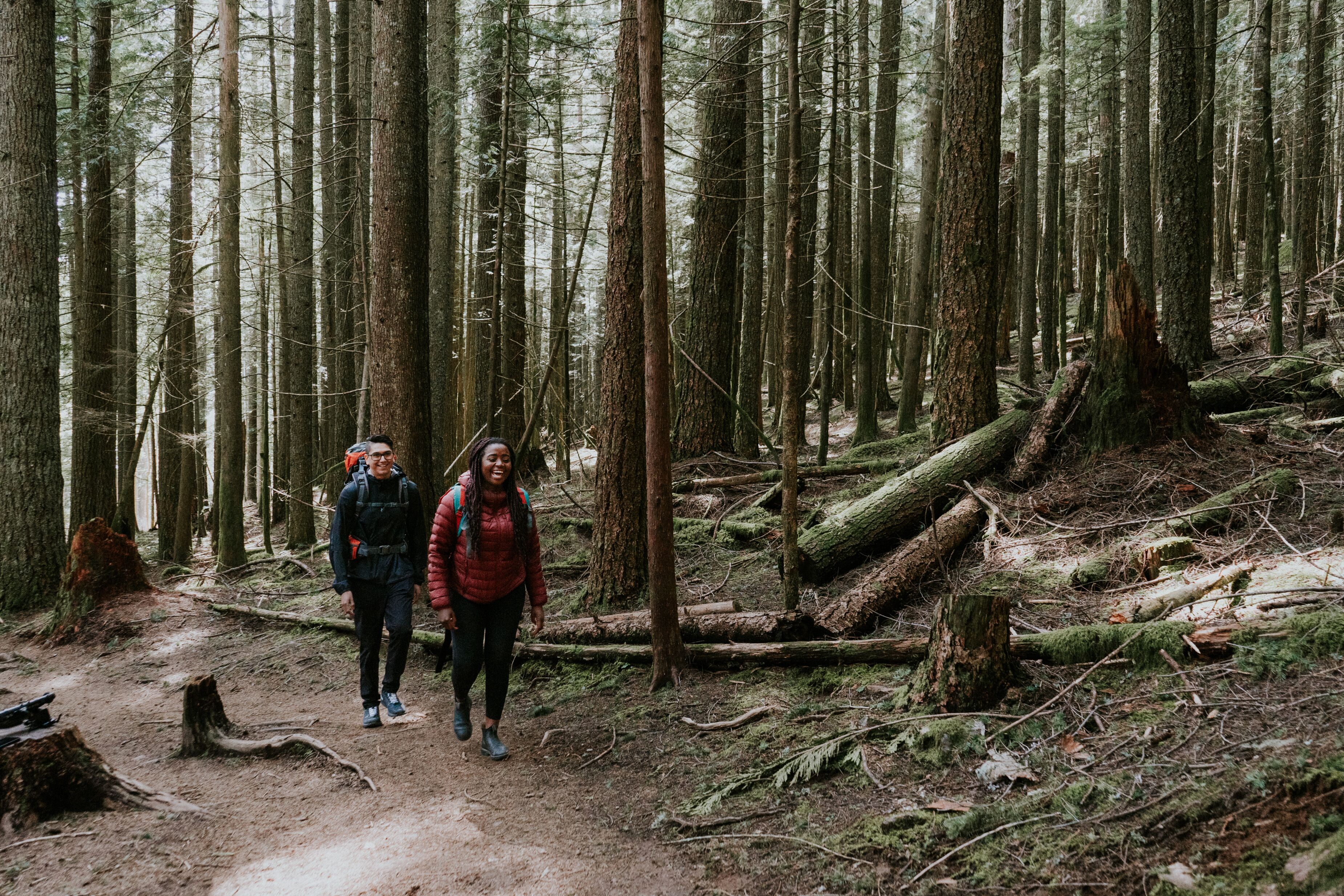 Two people smile and hike through a dense forest