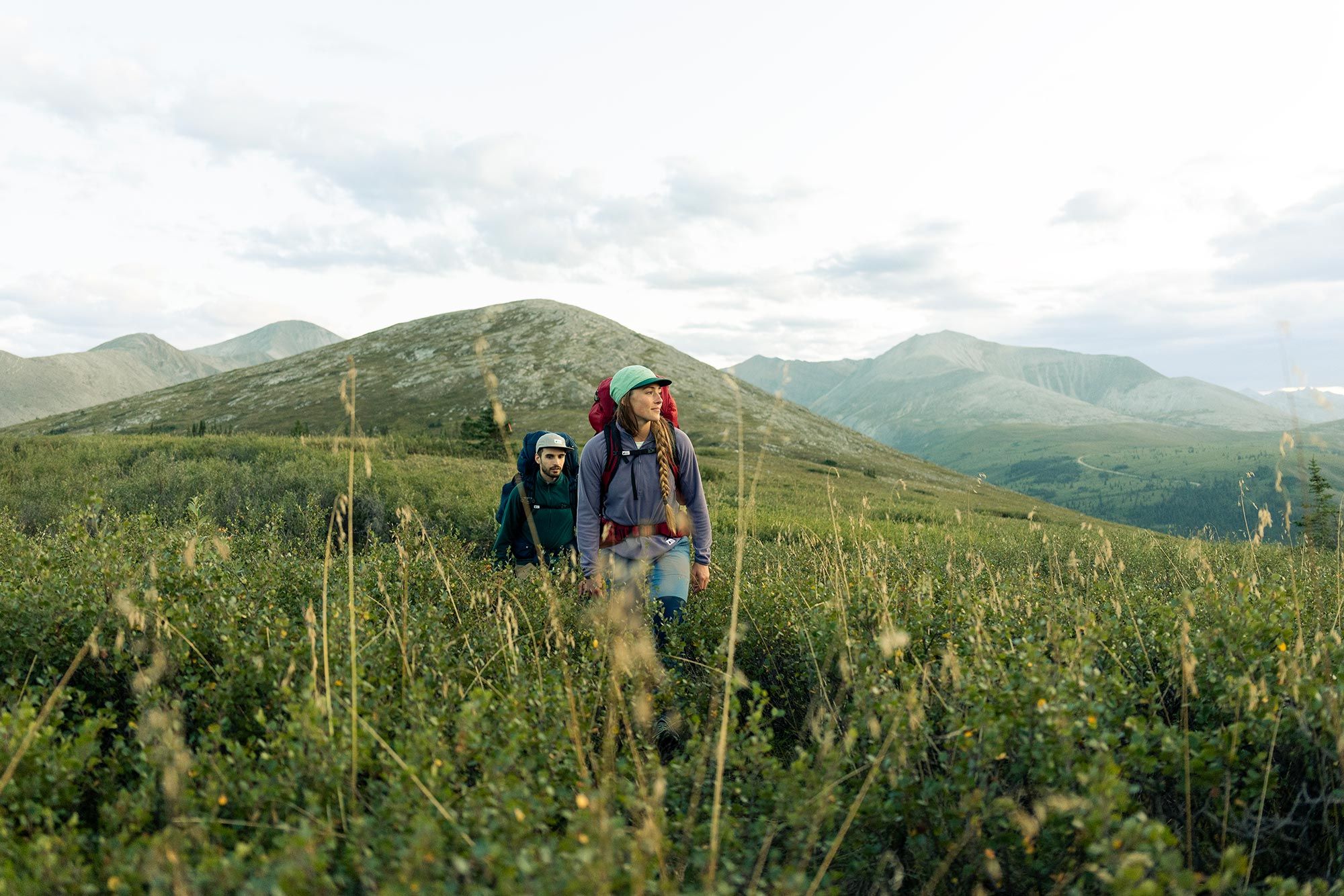Two people hike through long grass