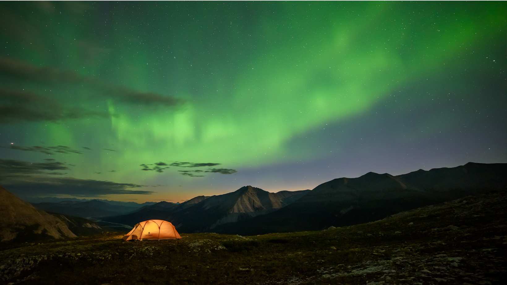 Campsite on mountain with Northern Lights in background