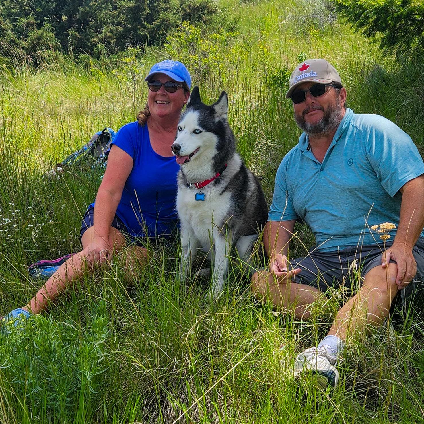 Leah and Rendal sit in a field with their dog