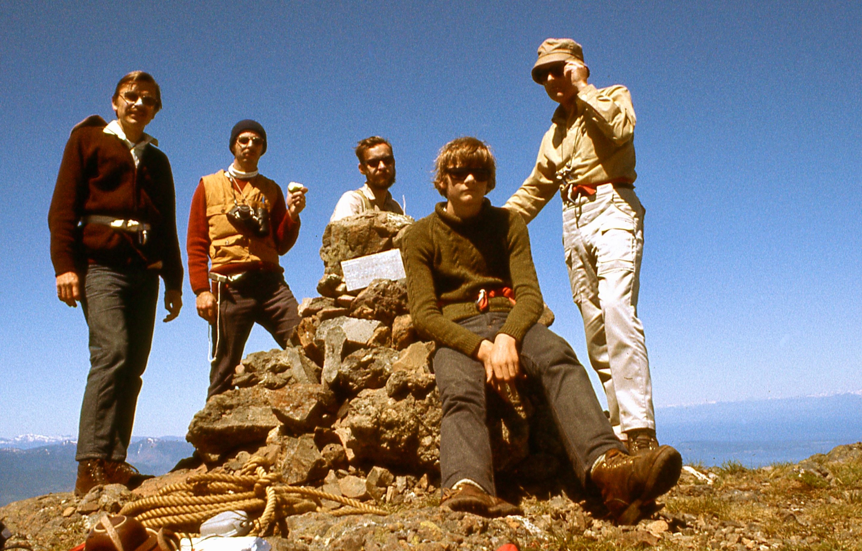 Group of climbers standing at the summit of Mount Arrowsmith beside a rock cairn.
