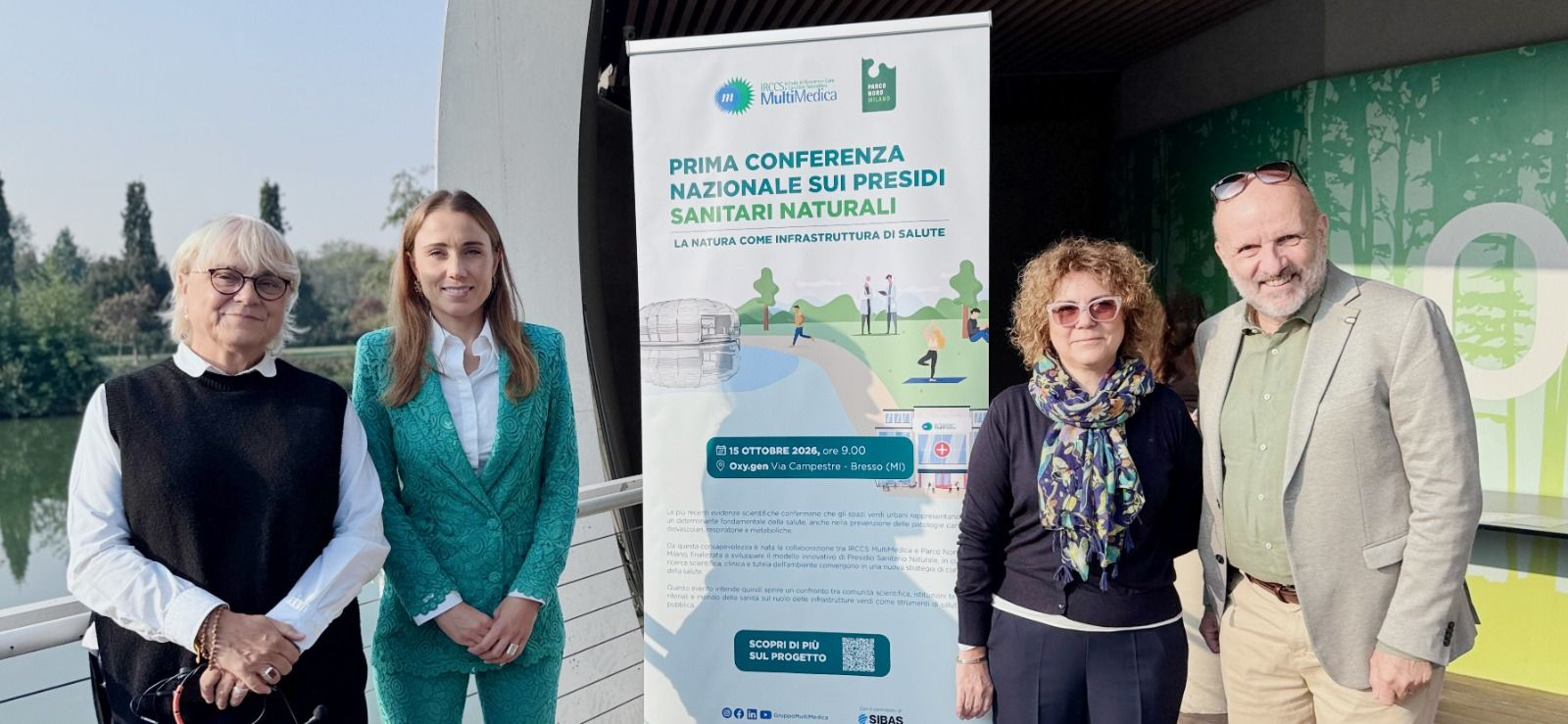 Four people posing beside a banner for First National Conference on Natural Health Presidia.