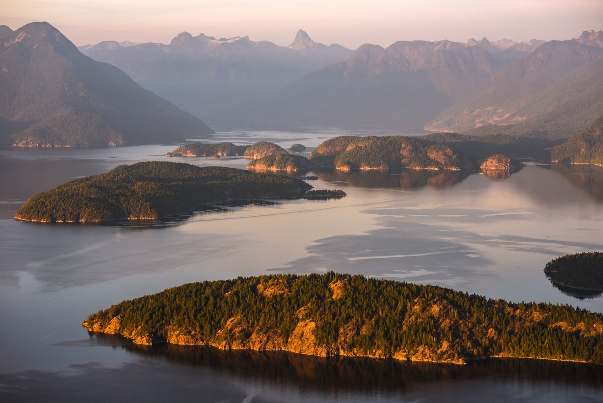 A series of tree covered islands scattered over a large body of water