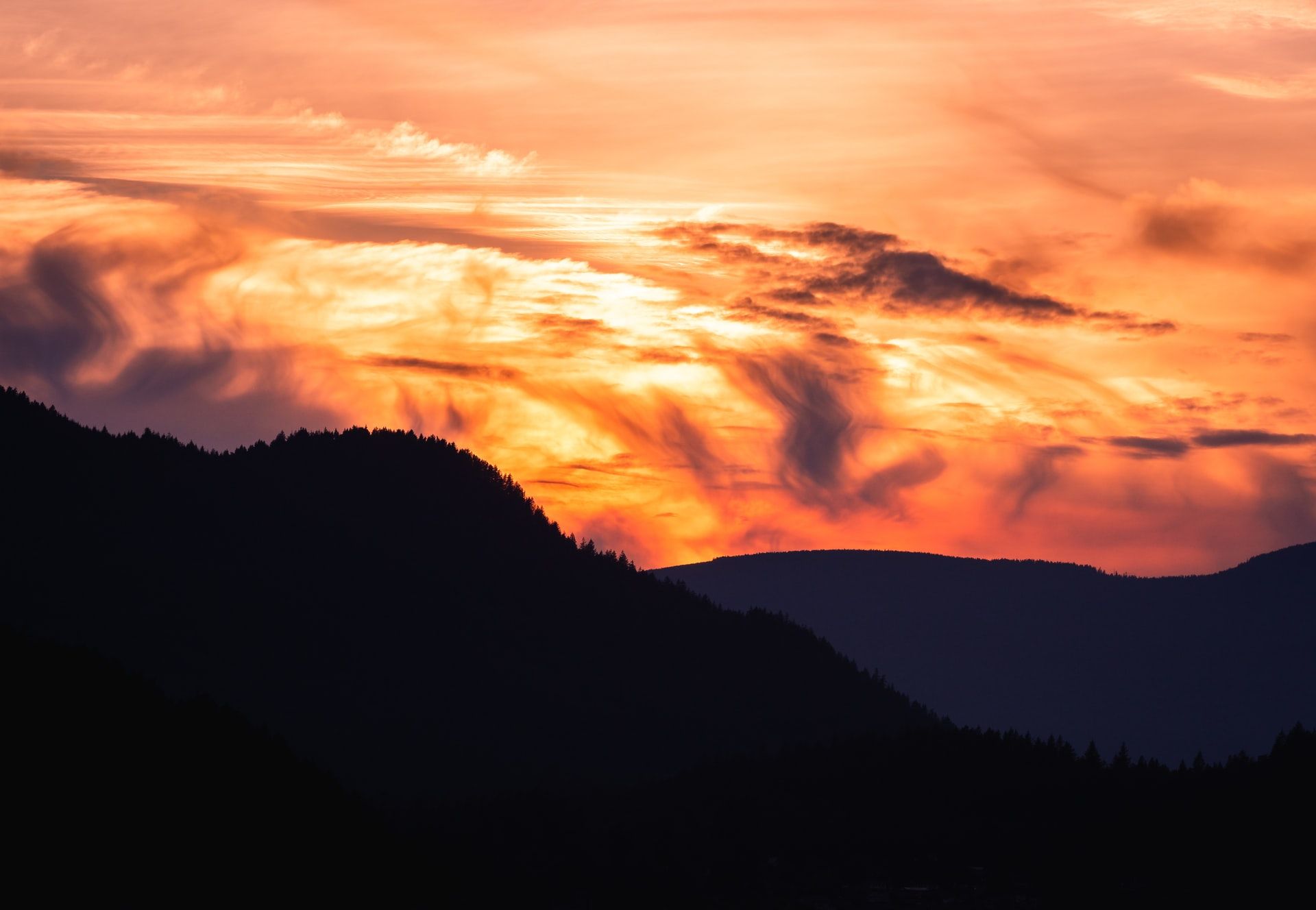 A sun sets in the background of a mountain region