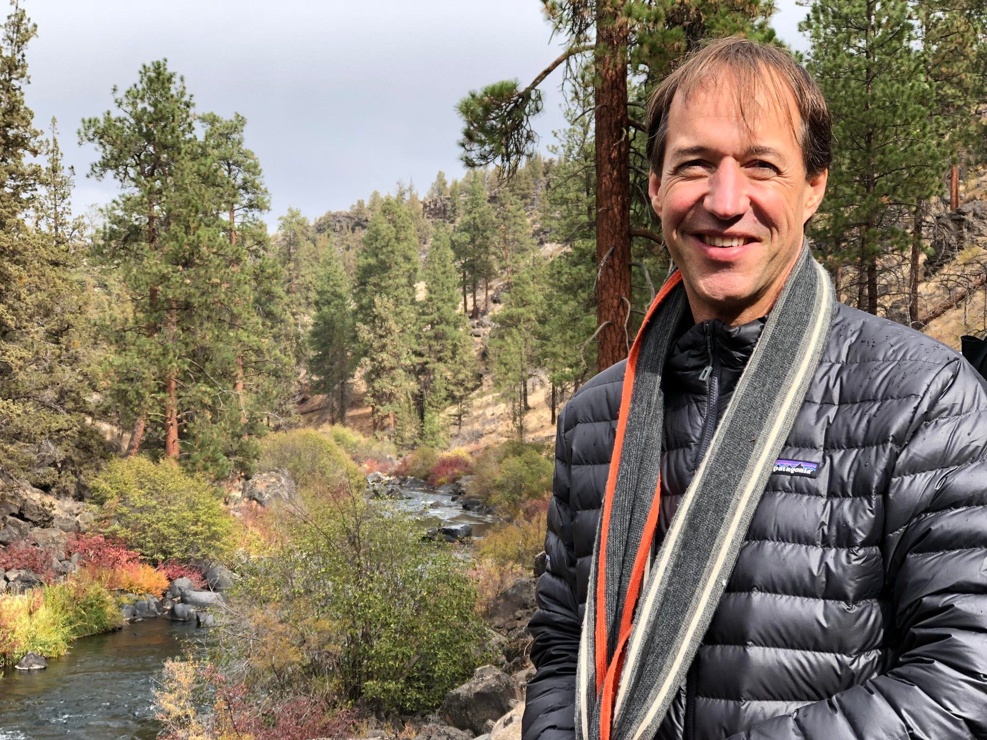 standing beside a forest stream surrounded by pine trees.