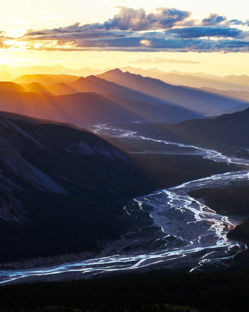 Sun shining over mountains and a stream