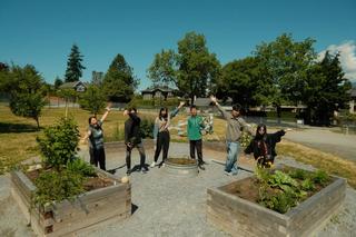 A group stands among raised garden beds outdoors.