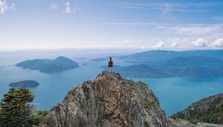 A person stands aloft a tall mountain