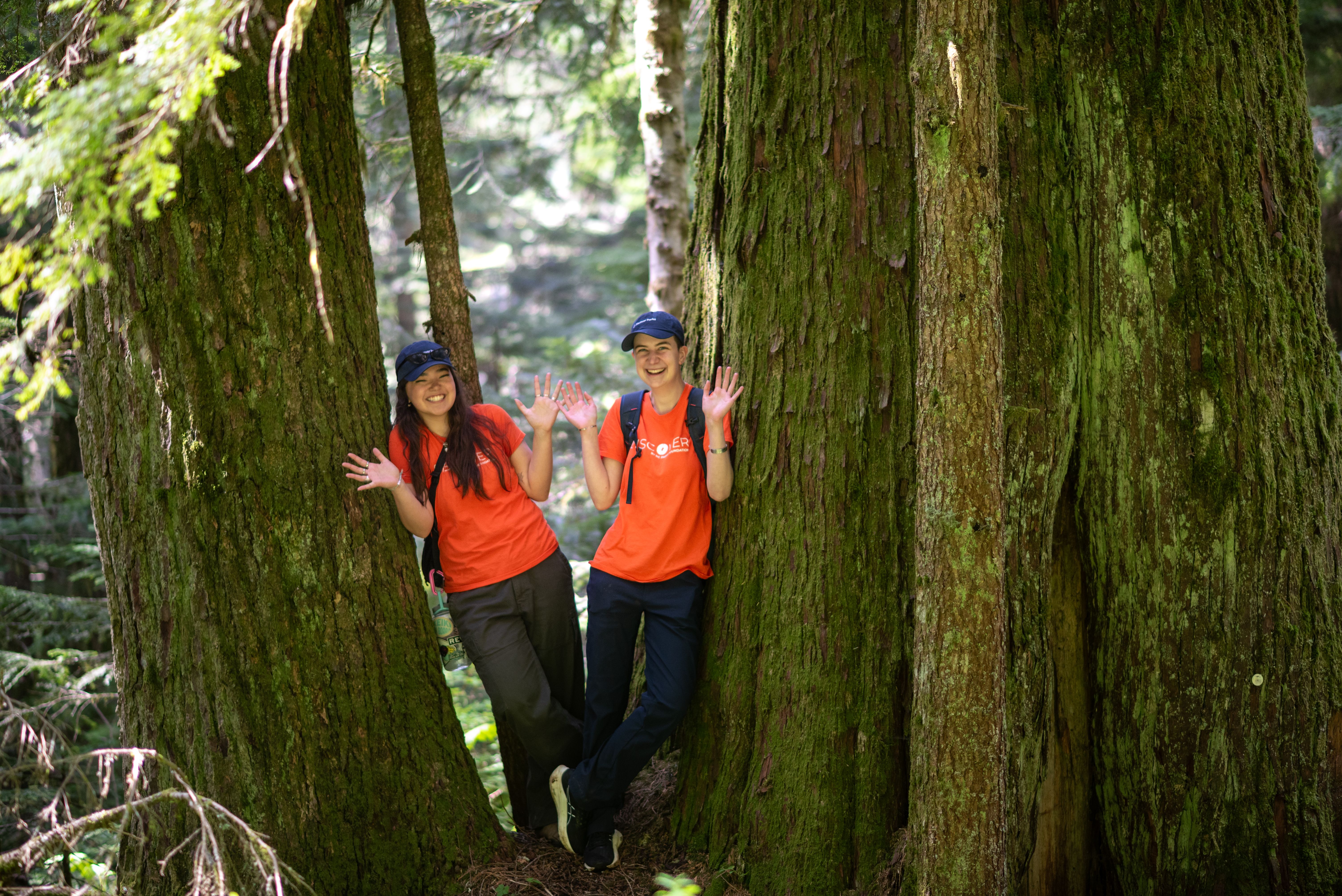 Two Discover Parks Ambassadors stand by a tree.