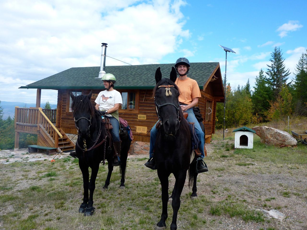 Karin and her partner Lisa on their horses, Link and Rollie. In the background, the log cabin (which no longer exists), affectionately referred to as "the Alm."