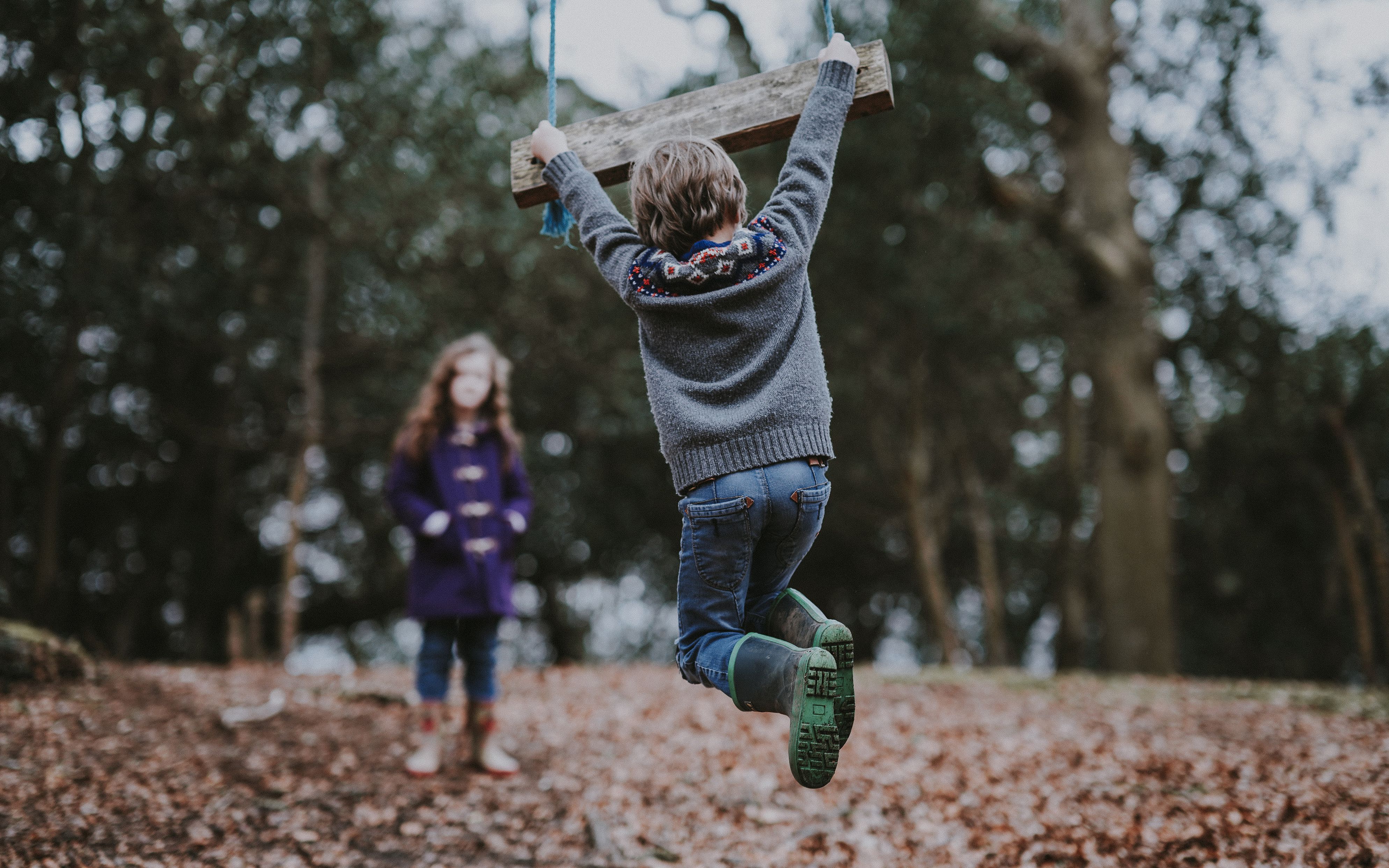 Children play in the leaves with a swingset