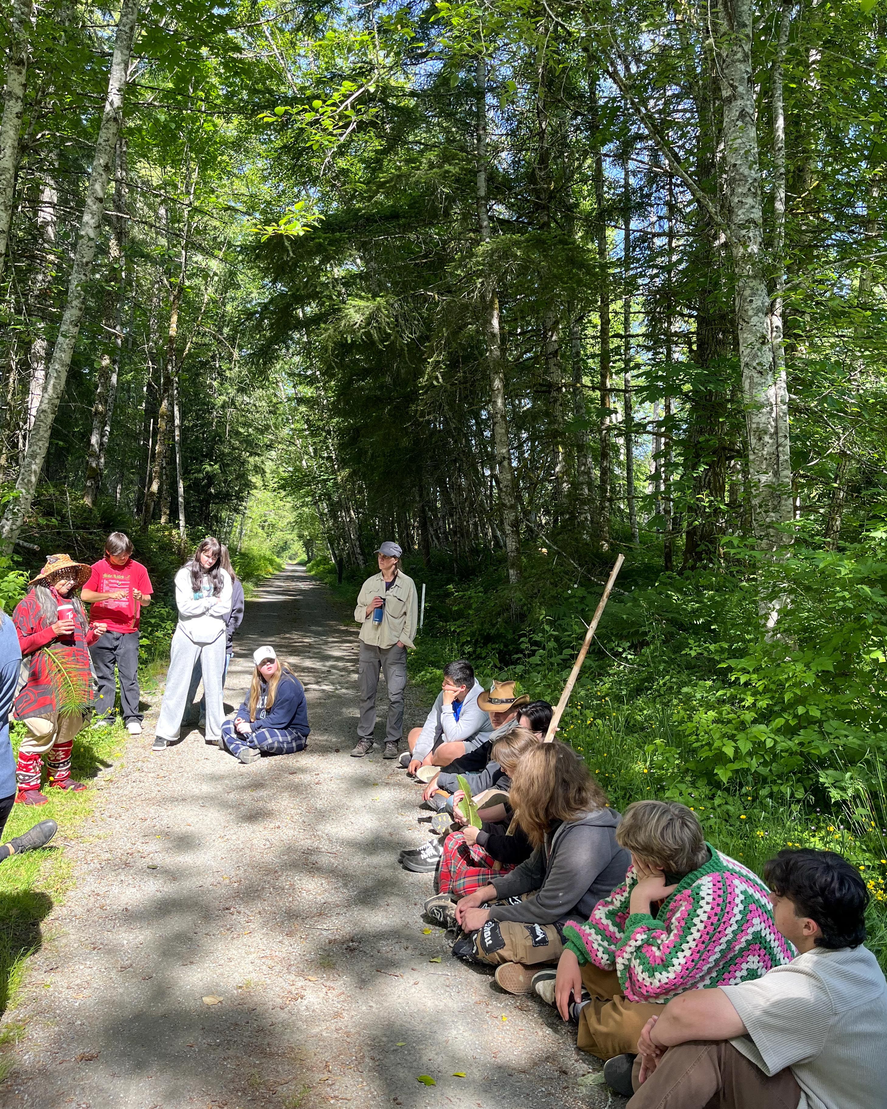 The campers listen as Huyamisé Della Rice Sylvester shares knowledge about sword fern medicine.