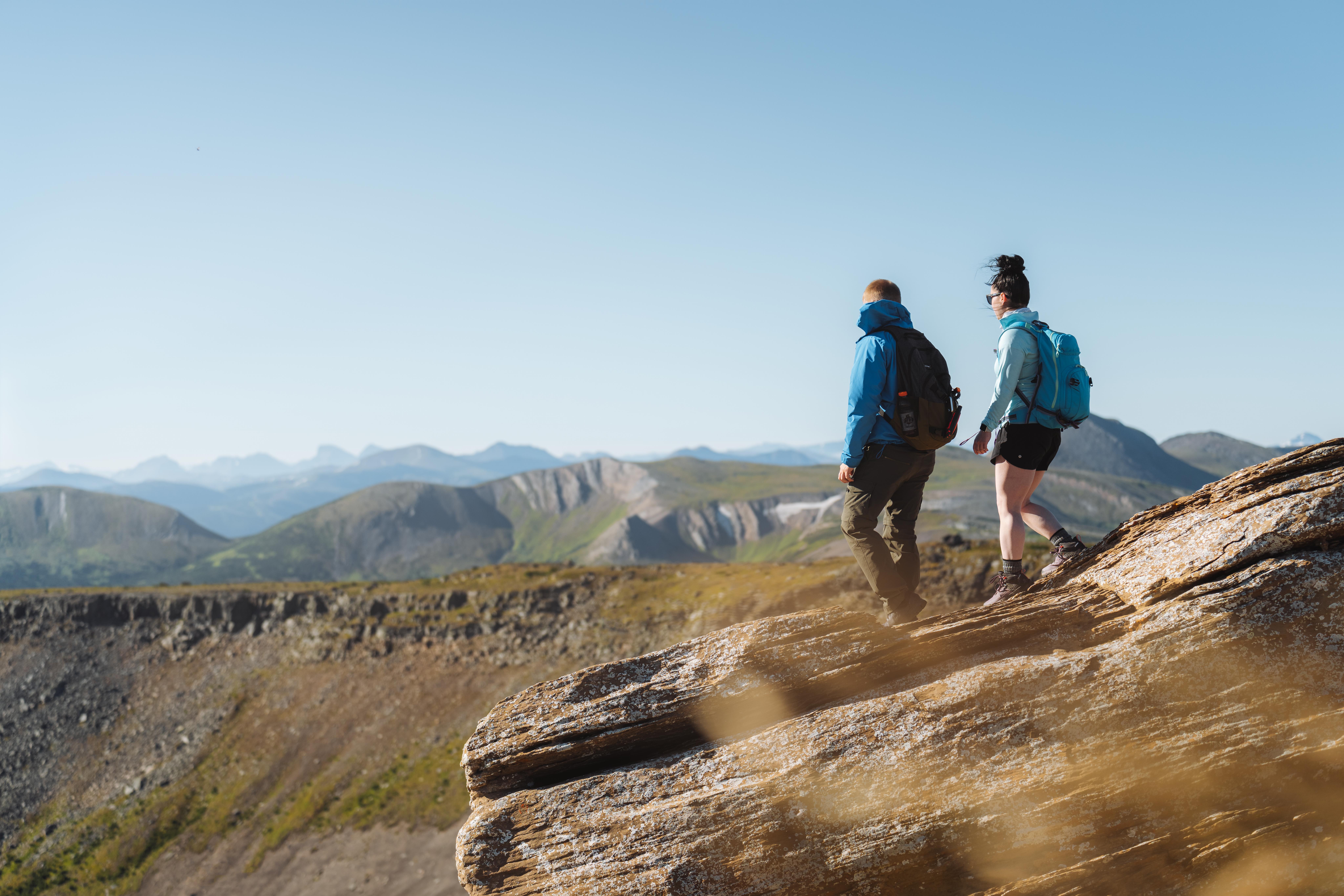 Two hikers traverse a mountain ridge