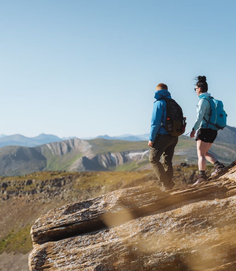 Two hikers overlook a valley from a rock face