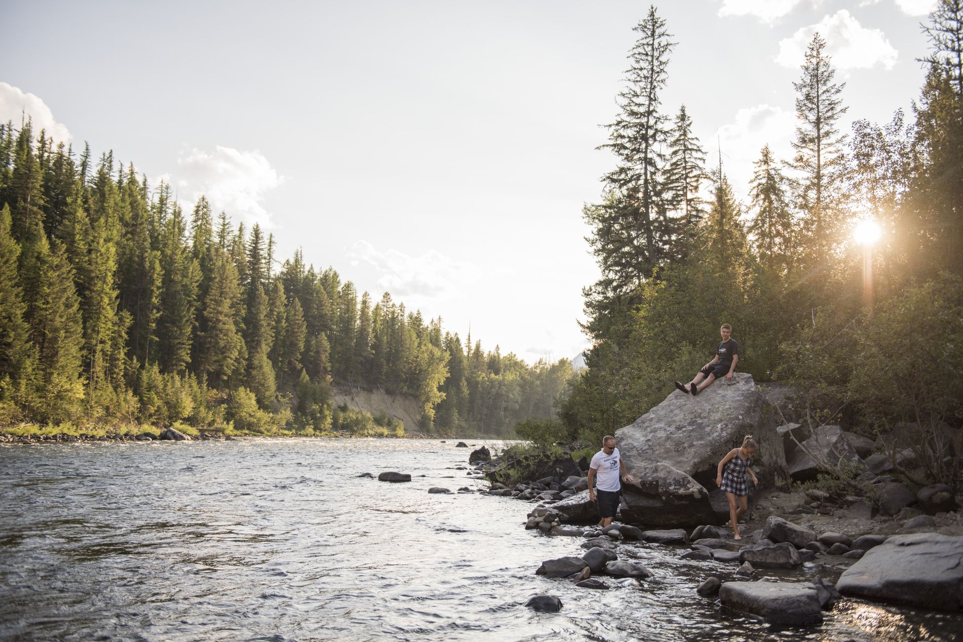 People relaxing in nature at the edge of a shallow river