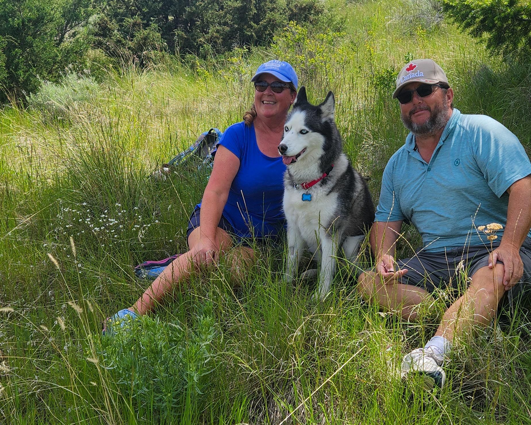 Leah and Rendal sit in a field with their dog