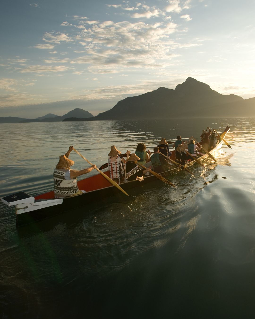 A crew of people row a boat across open water