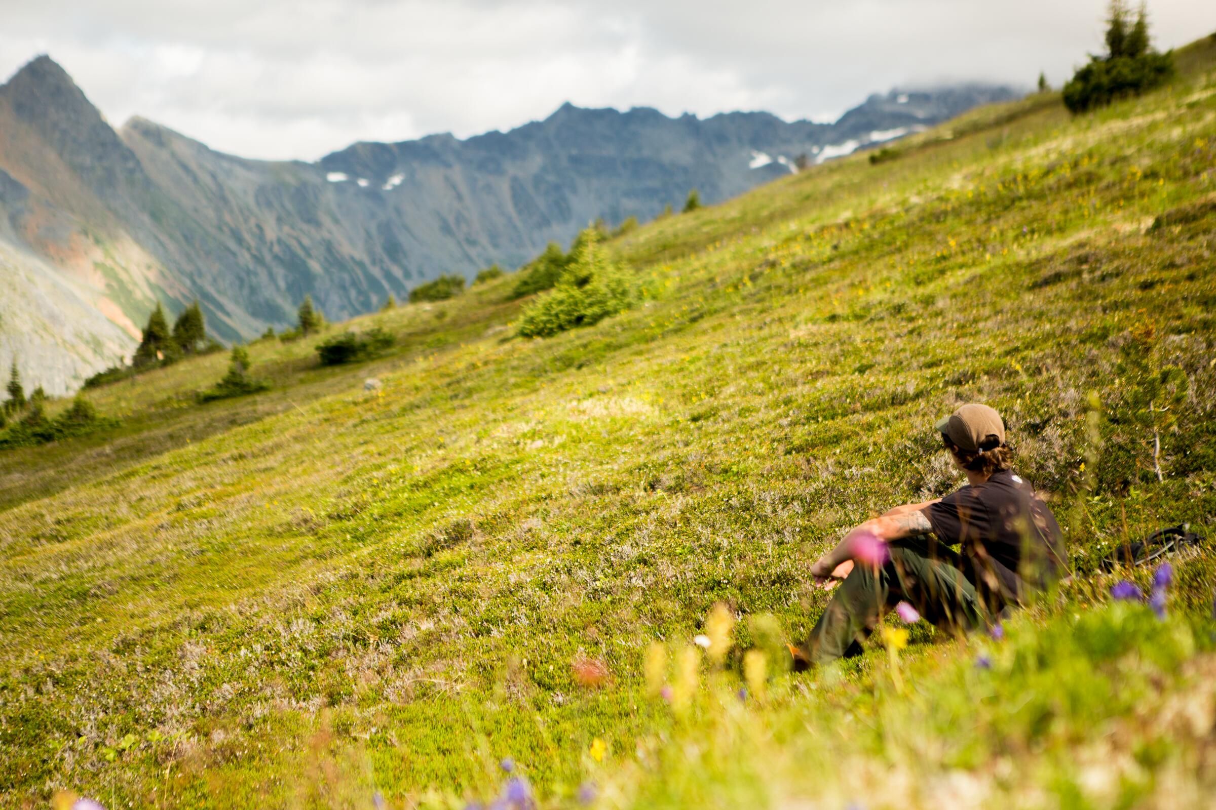 A person stops to rest on a grassy mountain