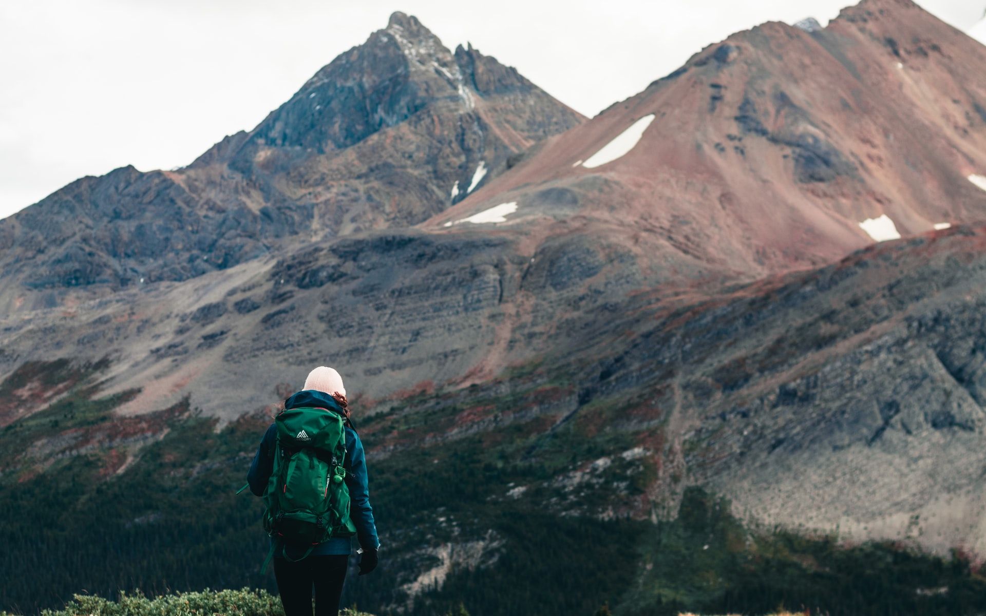 A person hikes with a large mountain in the background