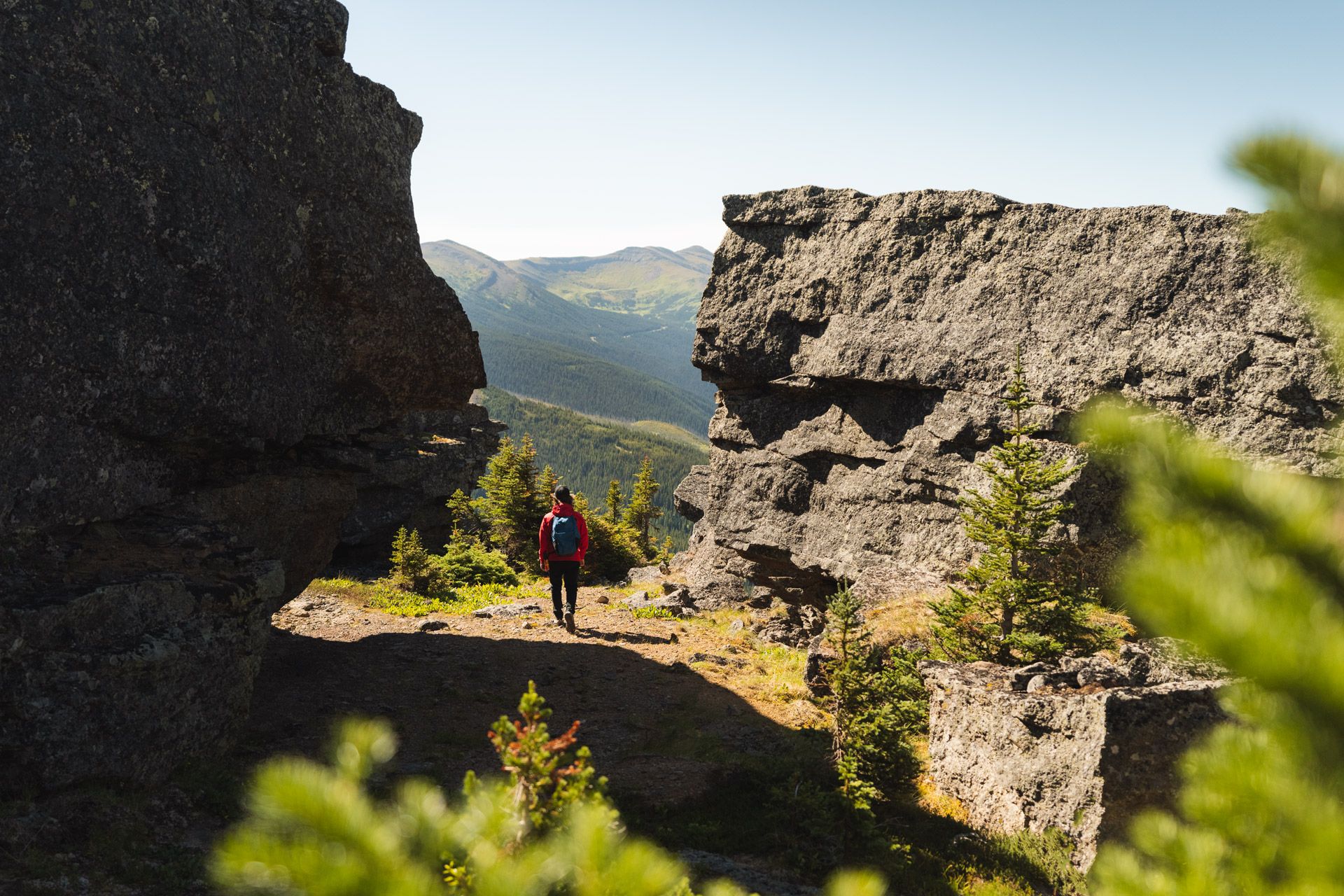 A hiker strolls between two large rock faces, opening out to a landscape view ahead