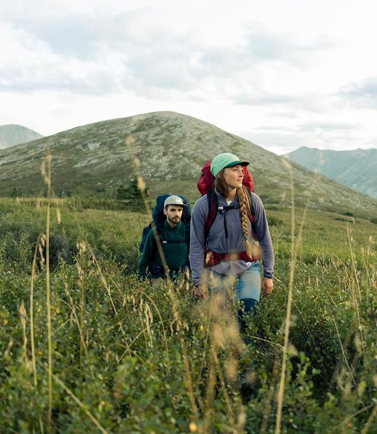 Two people hike through a field