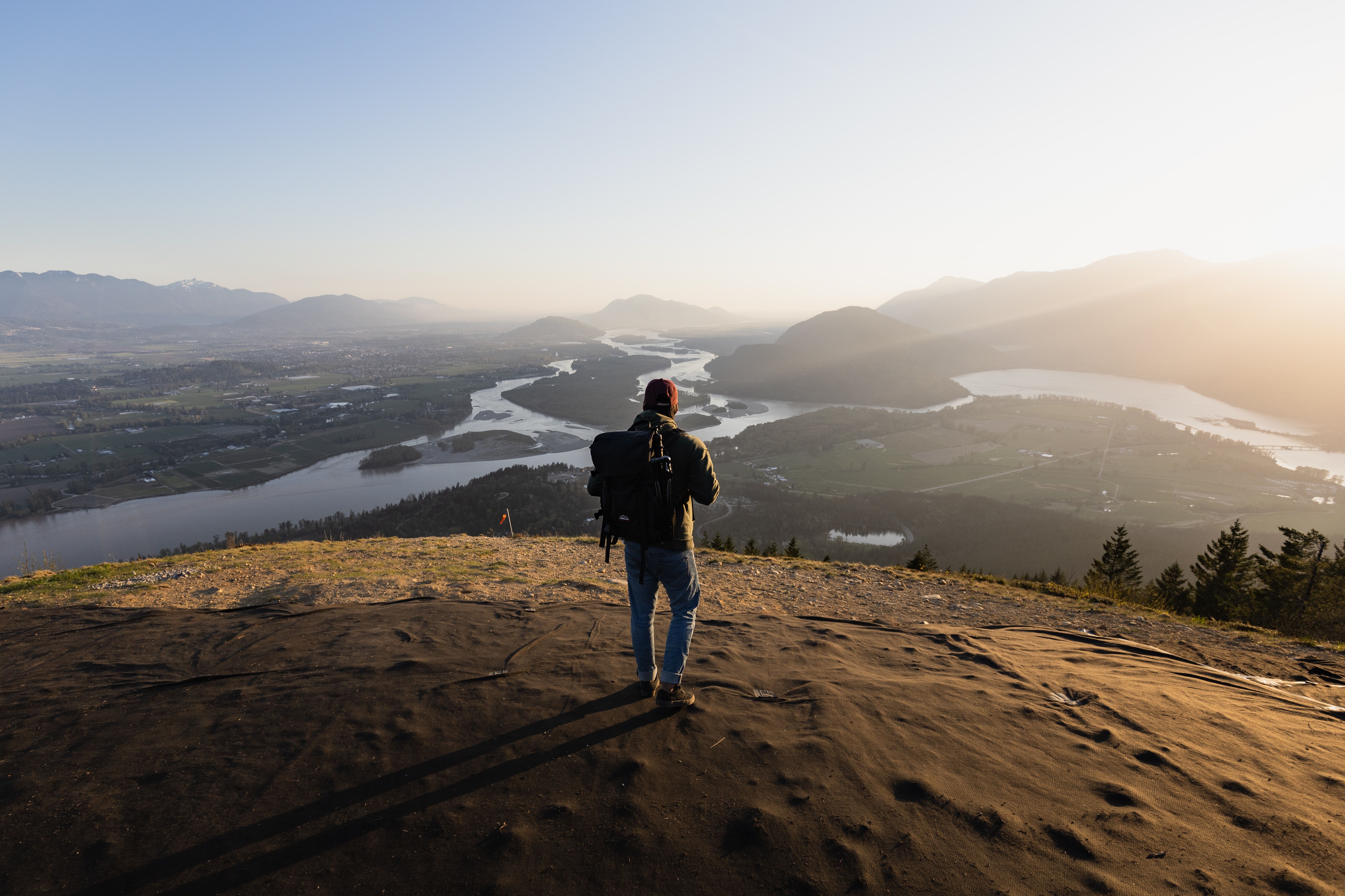A person looks over a meadow from a high hilltop