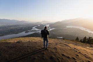 A person looks over a meadow from a high hilltop