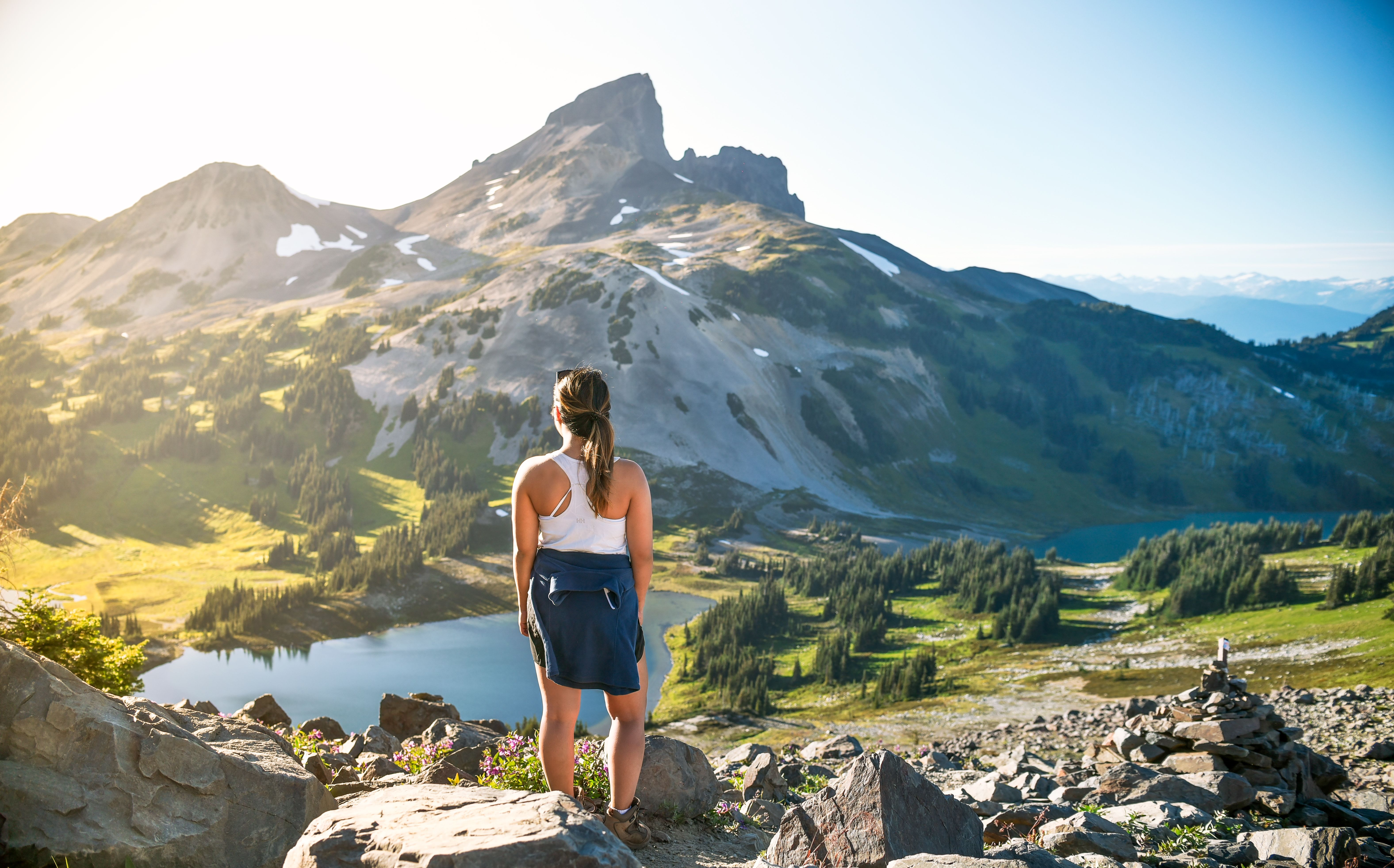 Standing woman looks over a lake and mountain range 