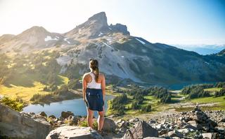 Standing woman looks over a lake and mountain range