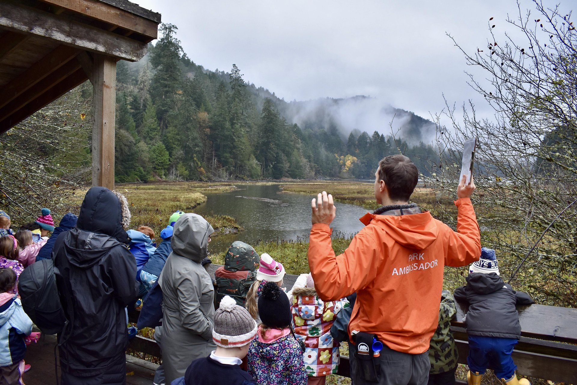 A park ambassador speaks to a group of children on a viewing platform.