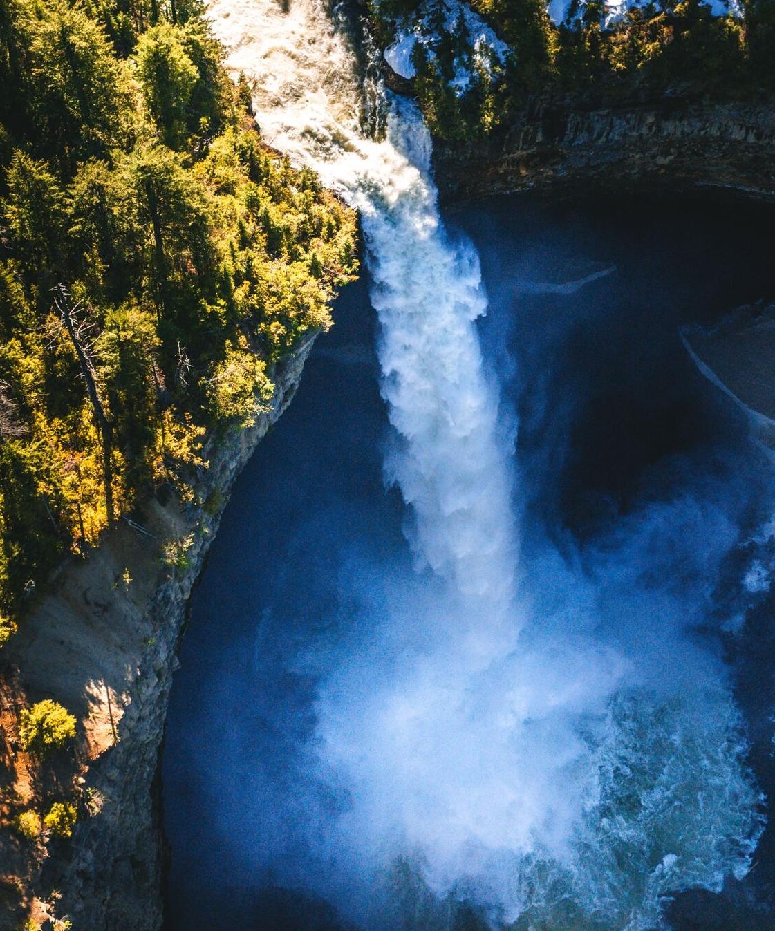 An aerial view of a waterfall pouring into a deep rocky canyon.