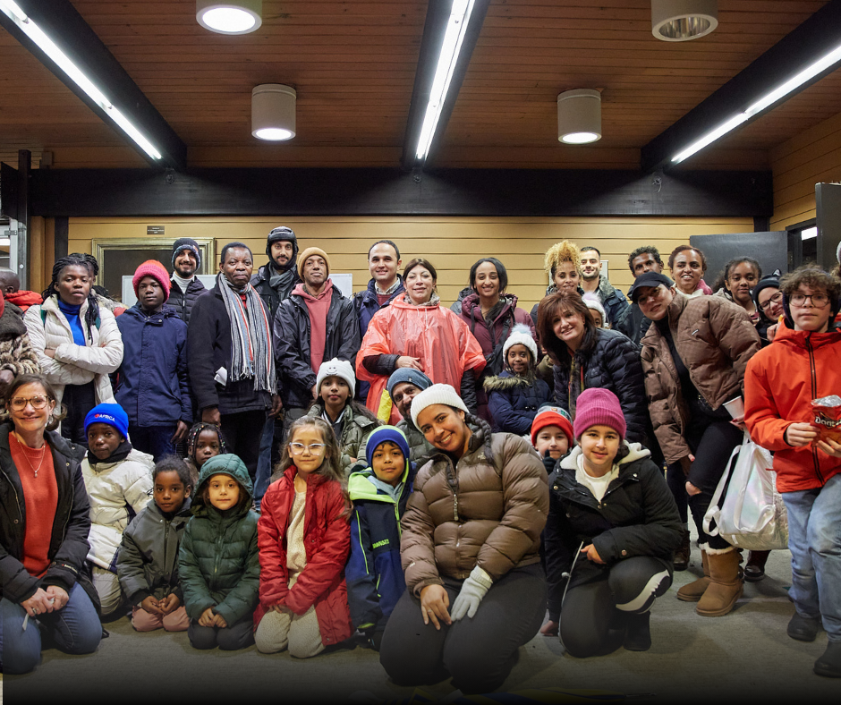 Large group of adults and children posing indoors for a group photo.